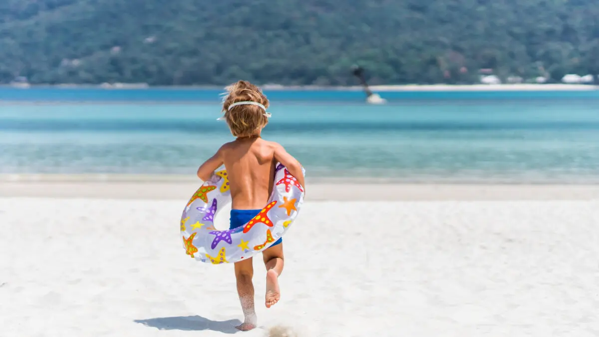 Rear view of carefree kid running with swimming tube towards sea. πνιγμός παιδιά